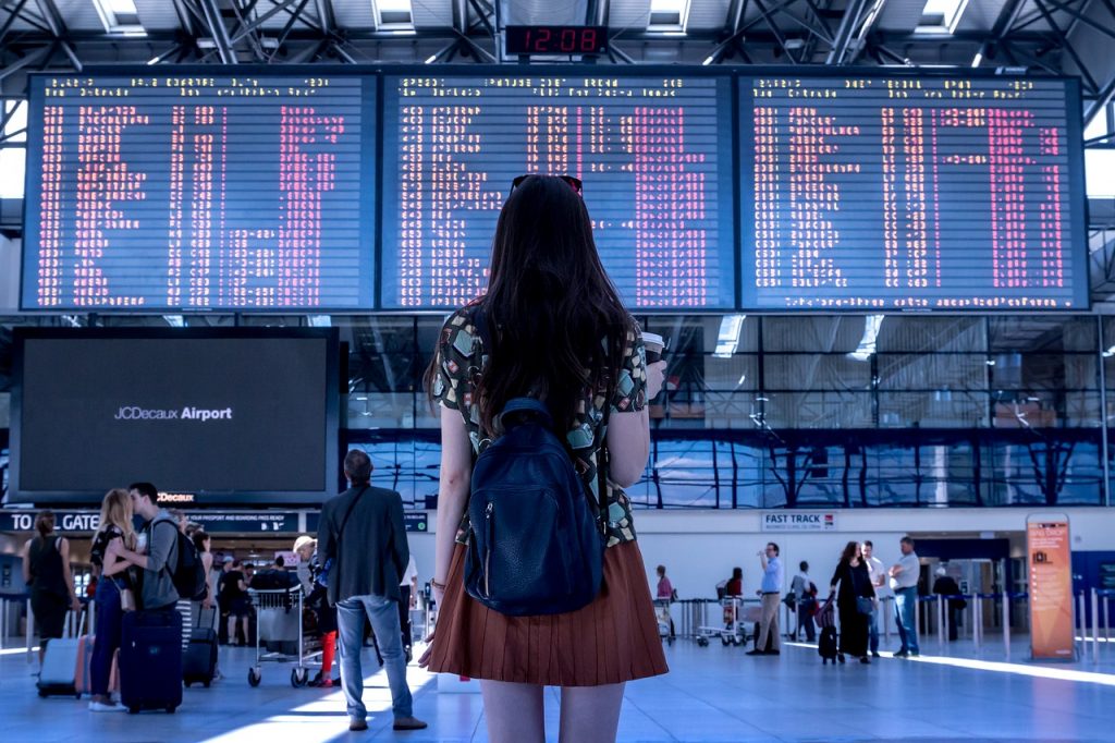 An illustrative photo of a woman standing in an airport. Photo by Pexels
