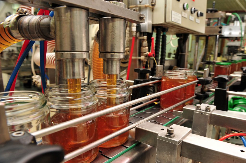 A machine fills jars with honey in a production line in Yad Mordevhai, Israel. Deposit Photos