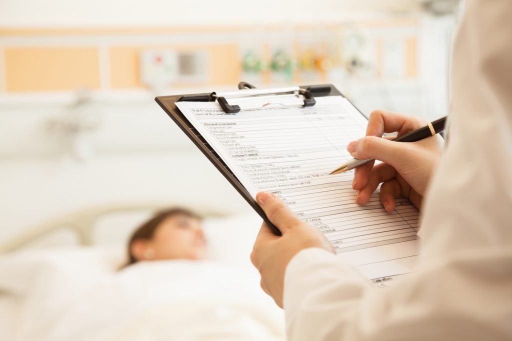 An illustrative photo of a person writing in a medical chart. Deposit Photos