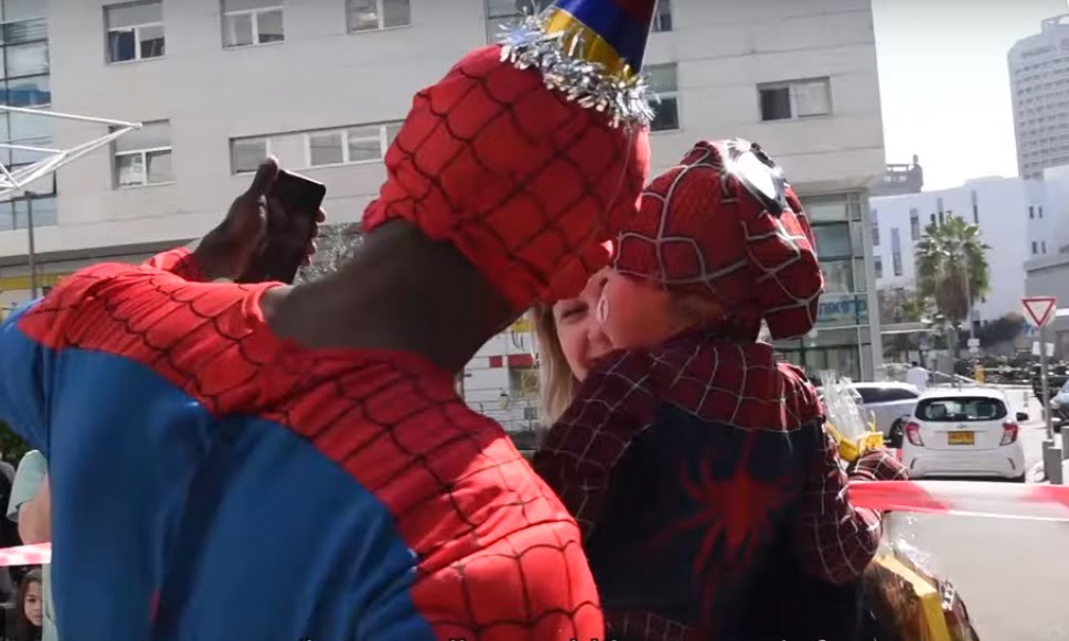 A volunteer dressed as Spider-Man takes a pictures with a young child at Ichilov's Children's Hospital in Tel Aviv for purim. Screenshot