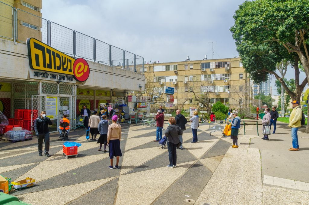 People follow the social distancing rules while waiting outside a supermarket in Haifa, Israel. March 2020. Deposit Photos