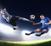 Two soccer players in mid air kicking the soccer ball
