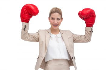 A smiling businesswoman holding boxing gloves via Nick Karvounis/Unsplash