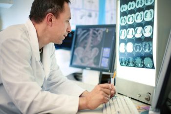 Illustrative: A doctor looking at a CT scan. Photo via Deposit Photos