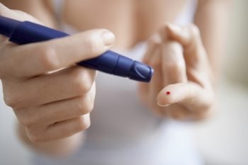 A woman performing a blood test on herself. Deposit Photos