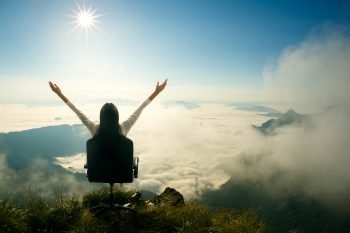 A woman sitting on a mountain top. Illustrative. Deposit Photos