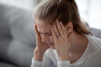 Illustrative photo of a person with a migraine. Deposit Photos