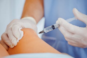 An illustrative photo of someone administering an injection. Deposit Photos