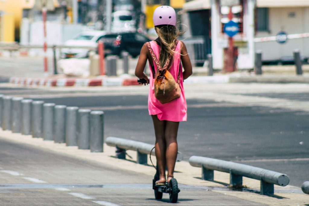 A girl rides her electric scooter on an afternoon in Tel Aviv. Deposit Photos