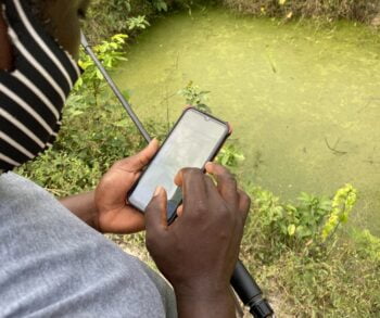 A field worker uses ZzappMalaria to scan bodies of water set for treatment. Courtesy